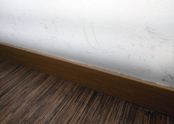 Scuffed White Wall and Wooden Trim in Interior Space A close-up view of a scuffed white wall with visible marks, contrasted by a sleek wooden trim. the space features a textured wooden floor, adding warmth to the minimalist interior setting. scuff marks photos stock pictures, royalty-free photos & images