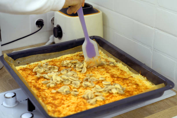 A close-up view of a cheesy pizza with mushroom toppings, freshly baked and still in the pan, with a slicing spatula.