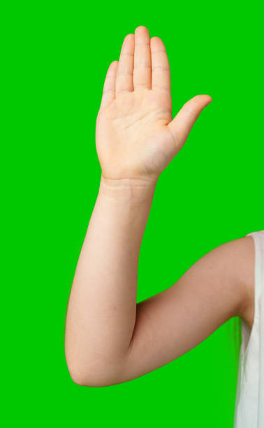 istock A child's hand raised in greeting against a bright green background 2190801168