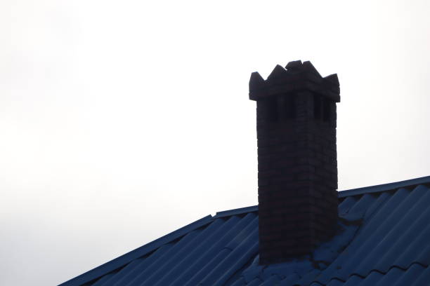 A beautifully crafted chimney design rises atop a vibrant blue roof, contrasting with the cloudy sky above