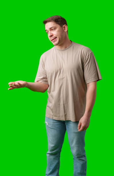 istock Man with a confused expression gestures with his hands against a bright green background 2190802694