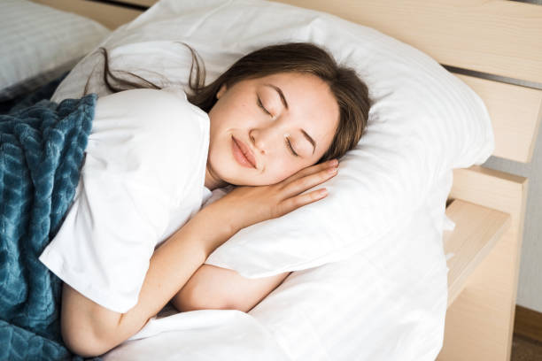 A beautiful young Caucasian brunette woman is sleeping on a bed.
