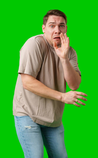 istock Man expressing fear while standing against a bright green background 2190803554