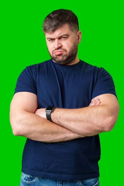istock Man expressing confusion with crossed arms in front of a bright green background 2190803831