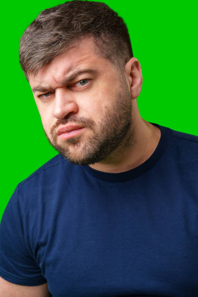 istock Man expressing confusion with crossed arms in front of a bright green background 2190804708