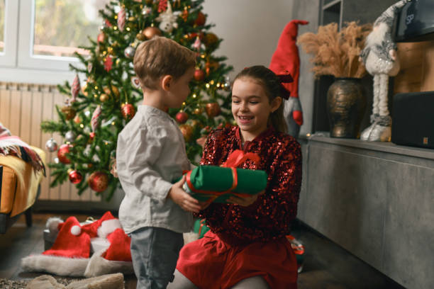 istock Older Sister Getting Excited When Receiving Surprise Gift From Younger Brother 2190806202