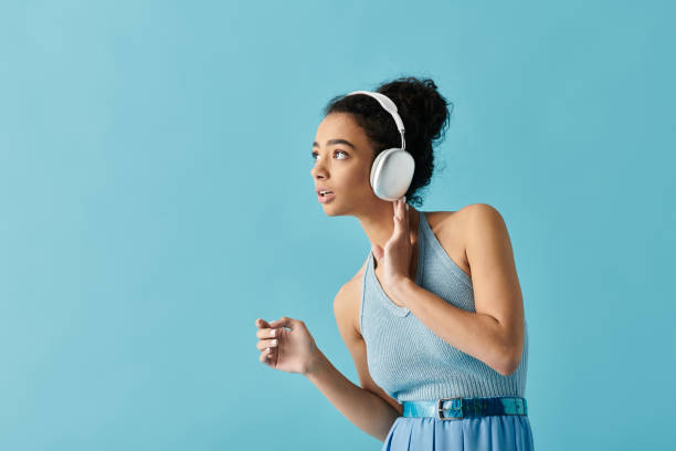 istock Young beautiful woman enjoying music while dancing against a vibrant blue backdrop 2190806426