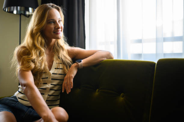 istock Serene woman relaxing on sofa looking out window, enjoying quiet moment 2190806601
