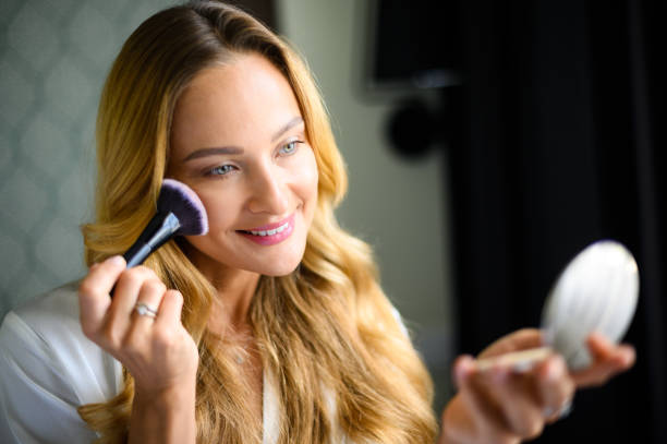 istock Smiling woman applying blush with a brush and looking in the mirror 2190806630