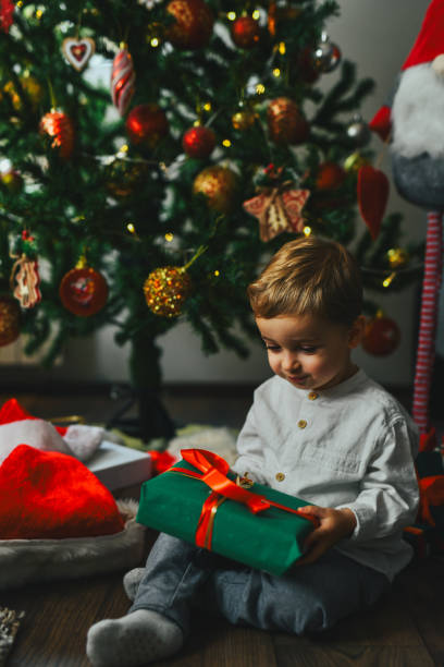 istock Smiling Boy Toddler Examining Christmas Gift He Found Under Fir Tree 2190806834