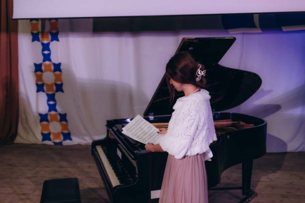 istock Young woman practicing piano at home and reading sheet music 2190806944