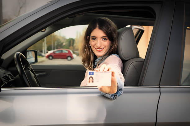 istock Young woman showing driving license from inside car 2190808051
