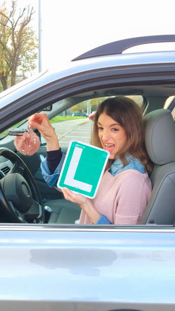 istock Young woman showing learner permit and car keys 2190808195