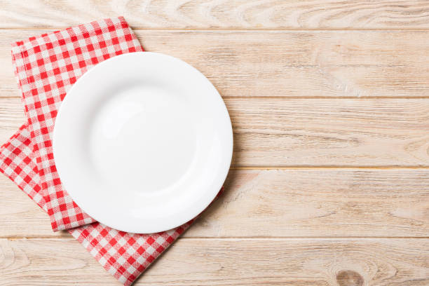 istock Top view on colored background empty round white plate on tablecloth for food. Empty dish on napkin with space for your design 2190808427