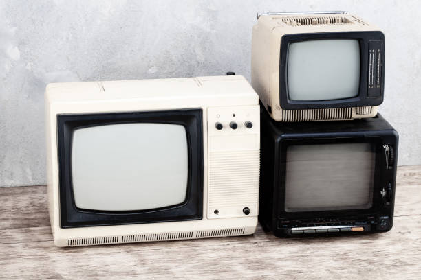 istock Old retro analog small TV sets stand on wooden floor front grey concrete wall background. 2190808922