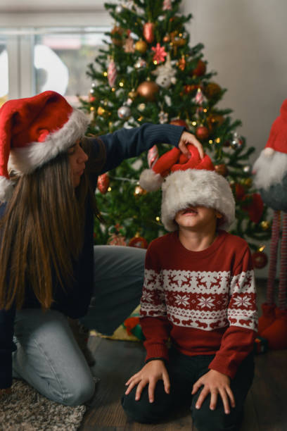istock Playful Aunt Teasing Nephew Covering His Eyes With Santa Hat 2190809700