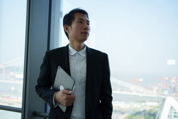 istock Business man standing by the glass window 2190812220