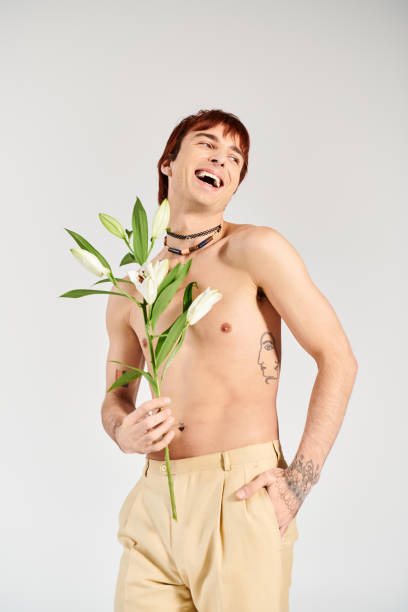 istock Fashionable young man expressing joy while holding fresh flowers in a minimalist studio 2190825859