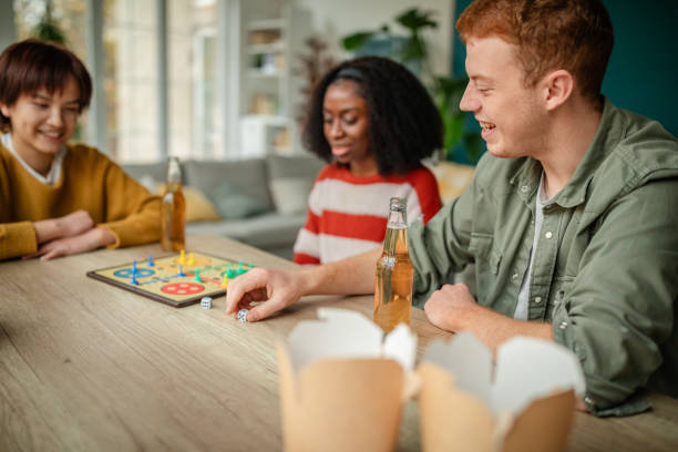 istock Three friends playing board game with drinks nearby 2190828579