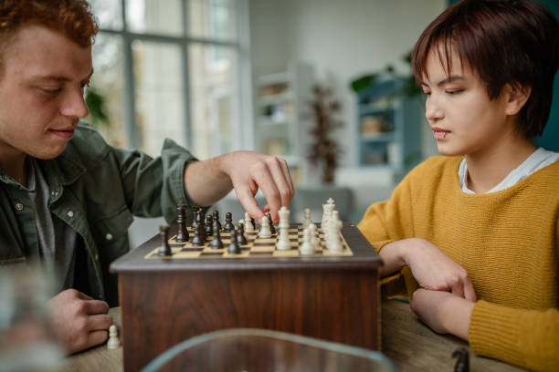 istock Concentrated pair intent on chess game, stylish room. 2190829006