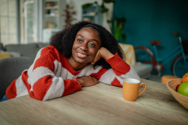istock Reflective woman smiling with orange mug on table. 2190829101