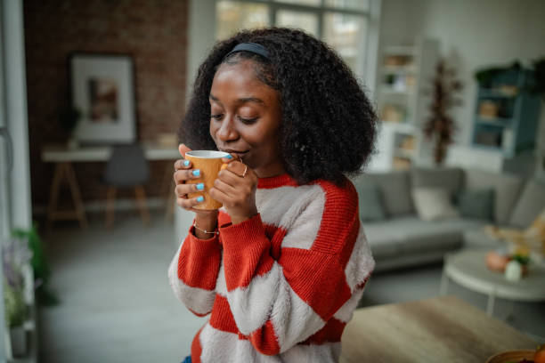 istock Joyful woman savoring hot drink in modern room. 2190829156