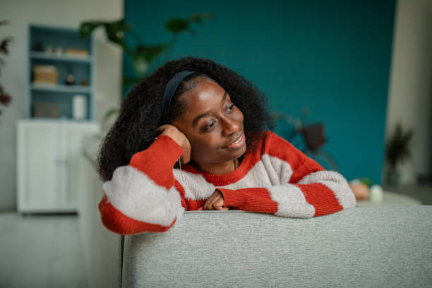 istock Thoughtful woman on sofa, gazes with gentle smile. 2190829197