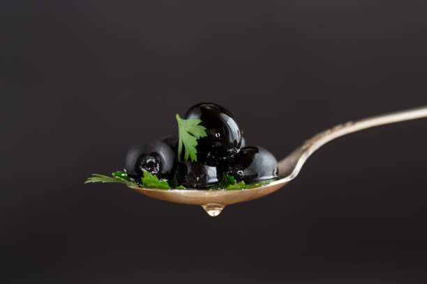 black olives in a spoon isolated on a black background.