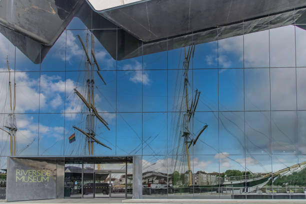 Glasgow, Scotland, UK- Riverside Museum designed by Zaha Hadid Architects along the River Clyde frontage and docked Victorian Tall Ship Glenlee reflected in glass facade