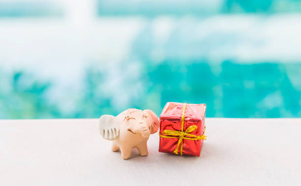 istock Little elephant clay sculpture with red gift box over blurred background 2190831053