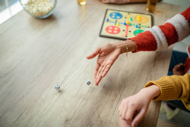 istock Friends rolling dice in a fun board game atmosphere 2190831931