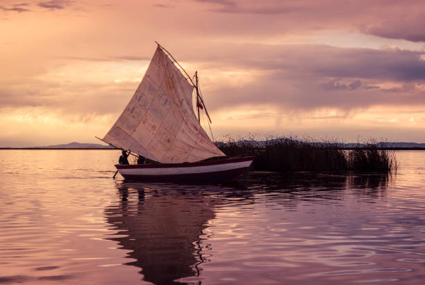 Traditional wooden boats floating in the Luguhu Lake, Yunnan, China. Lonely boat in lake with mountains and rainy clouds background.