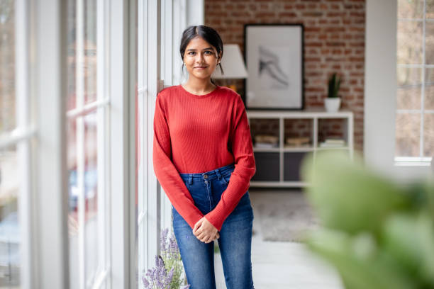 istock Woman in red leaning against window, serene setting 2190834069