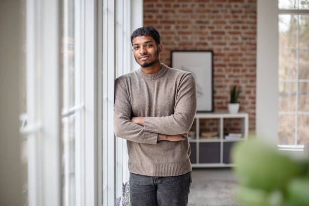 istock Man in gray sweater leaning against window, relaxed 2190834140