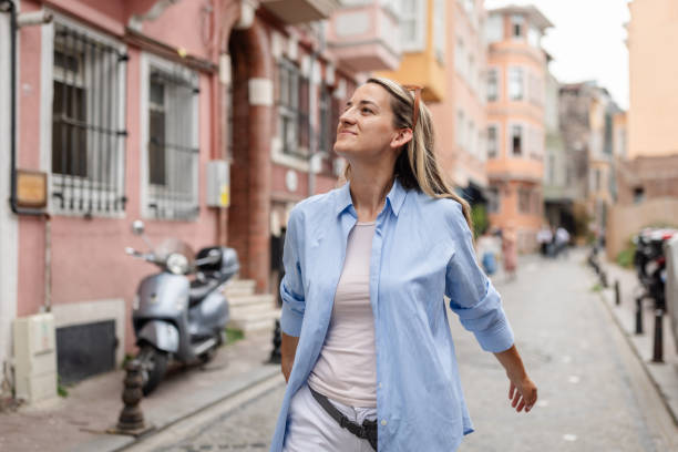 istock Woman with joyous expression strolls down city street 2190835128