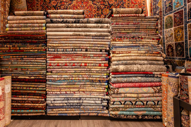 A rich array of textures and colors fills this carpet store, with carpets stacked wall-to-wall, offering a visual feast of traditional and timeless patterns.