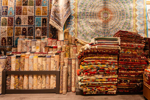 An eclectic shop with an array of carpets neatly arranged along walls, featuring vibrant, intricate designs in a colorful, warmly lit traditional setting.