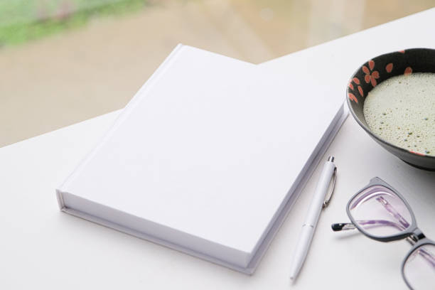 blank book mockup on white wooden coffee table with green matcha tea near window, asian style