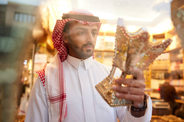 istock A Middle Eastern man holds and admires a censer inside a shop, appreciating its craftsmanship. 2190843730