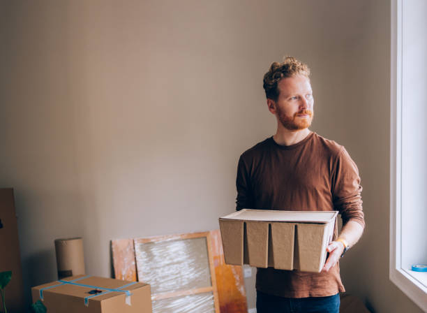 istock Man Holding Carton Box in Minimalist Interior During Relocation 2190846950