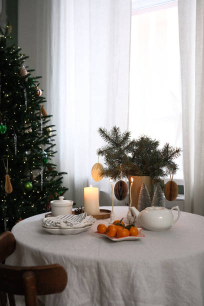 istock A beautifully warm and inviting Christmas holiday table decor with plates, candles, vase with spruces branches, teapot, mandarins. 2190851189