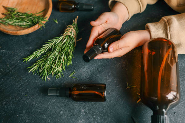 istock Amber glass spray bottle with a black cap placed on a dark rustic surface, surrounded by rosemary sprigs and natural decor elements. Concept of natural, eco-friendly cosmetics or aromatherapy products 2190851307