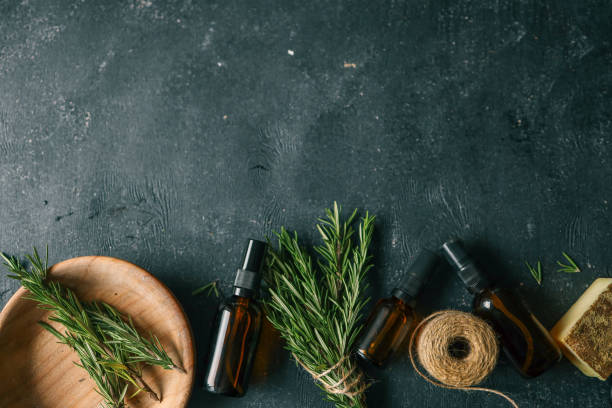 istock Amber glass spray bottle with a black cap placed on a dark rustic surface, surrounded by rosemary sprigs and natural decor elements. Concept of natural, eco-friendly cosmetics or aromatherapy products 2190851311