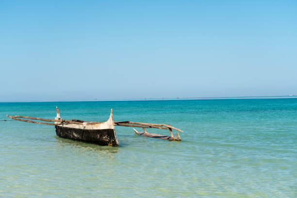 Fisherman piroga, fishing boa, waiting at the low tide coast against clear blue sky.