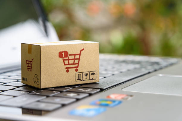 Online shopping and e-commerce: The future of retail. A miniature cardboard box with a shopping cart icon placed on a laptop keyboard, representing the integration of technology in retail commerce. compras online y comercio electrónico: el futuro del retail. una caja de cartón en miniatura con un icono de carrito de compras colocado en el teclado de una computadora portátil, que representa la integración de la tecnología en el comercio minorista