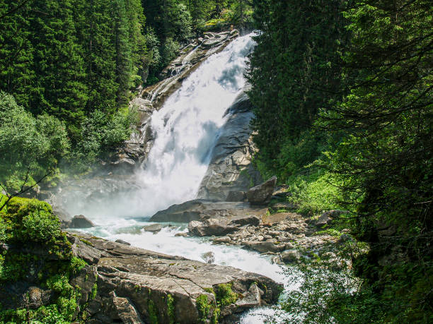 The force of water, flowing between trees and rocks at the Krimml Falls in Austria
