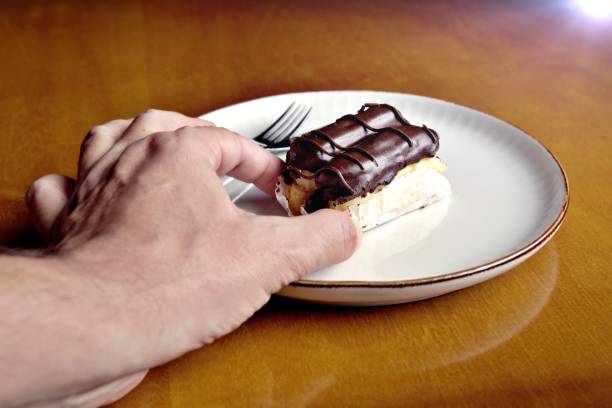 istock A man holds two eclairs on a plate between his fingers 2190854702
