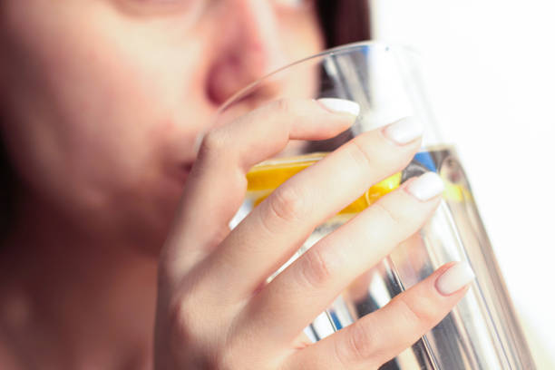 istock A young woman drinks water with lemon from a transparent glass 2190857869