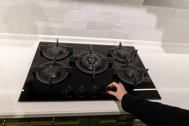 istock Woman's hand turns on a modern black gas stove in the kitchen 2190863375