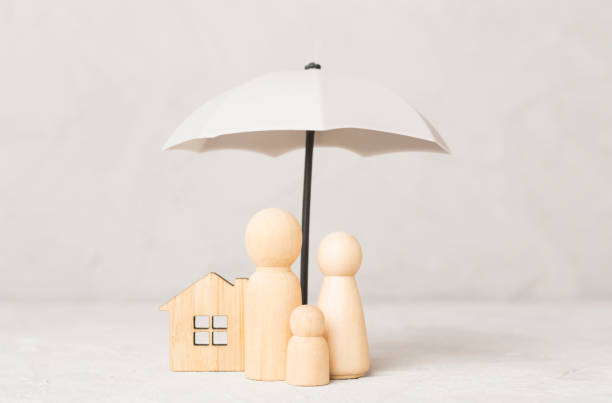 istock Wooden family figures under umbrella on concrete background.Insurance coverage concept. 2190872794